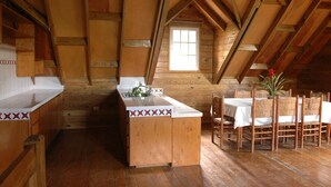 A wooden cabin with a kitchen area featuring a sink and a dining table with chairs. - Ranch Le Montcel (Carrefour)