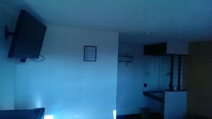 A room with a television mounted on the wall, a small framed picture, a sink, and a mirror in the corner. - Airport Lodge Wichita Kansas (Wichita)