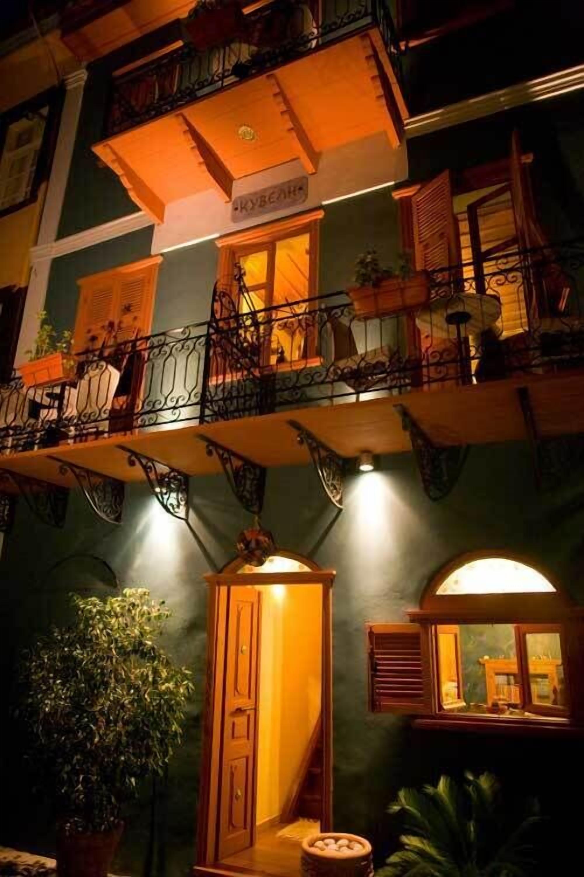 A multi-story building with balconies, wooden doors, and potted plants.