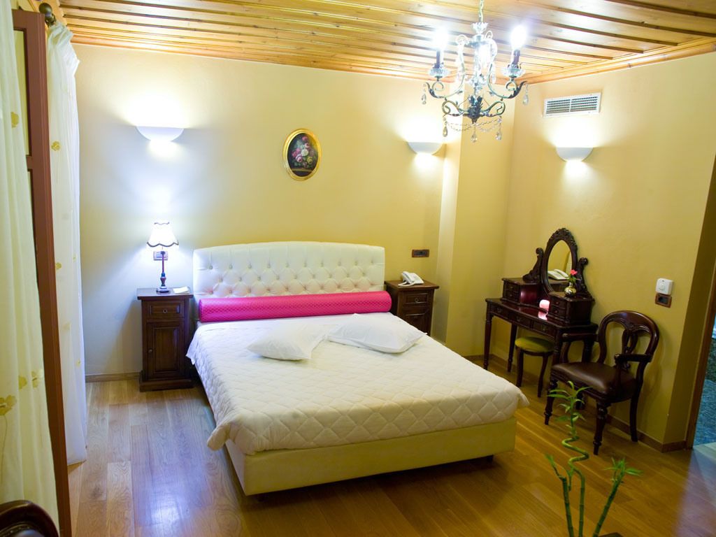 A bedroom with a large bed, bedside tables, a desk, and a chair.