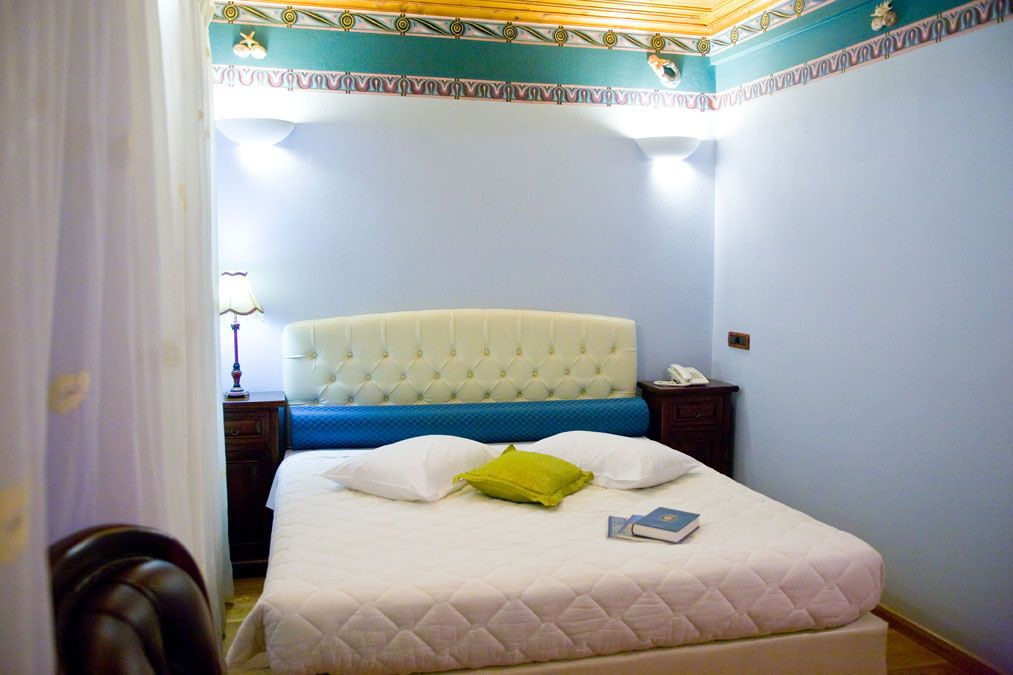 Un dormitorio con una cama grande, una mesita de noche, una lámpara y un techo decorativo.