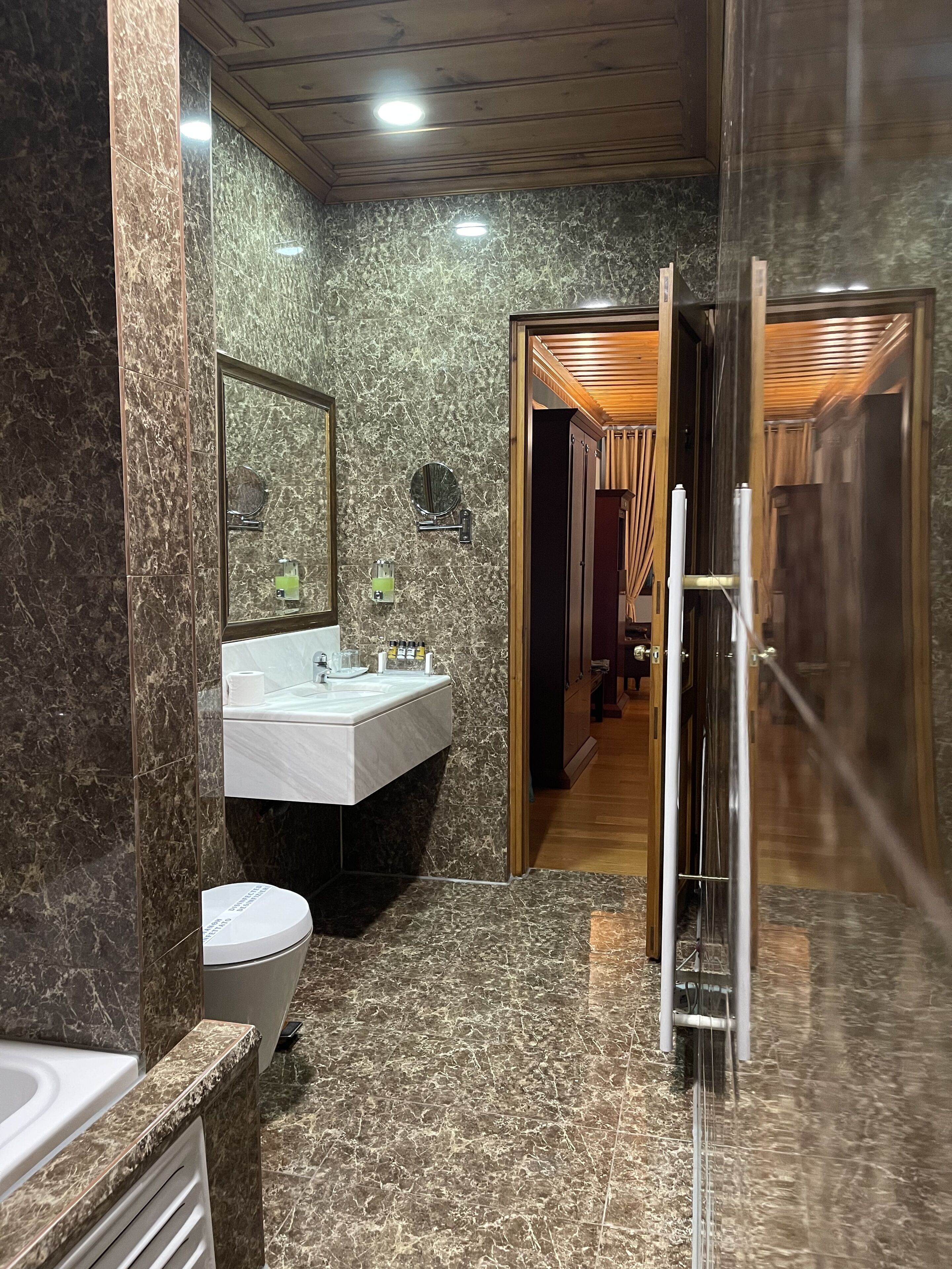 Un baño moderno con lavamanos de mármol, inodoro y zona de ducha.