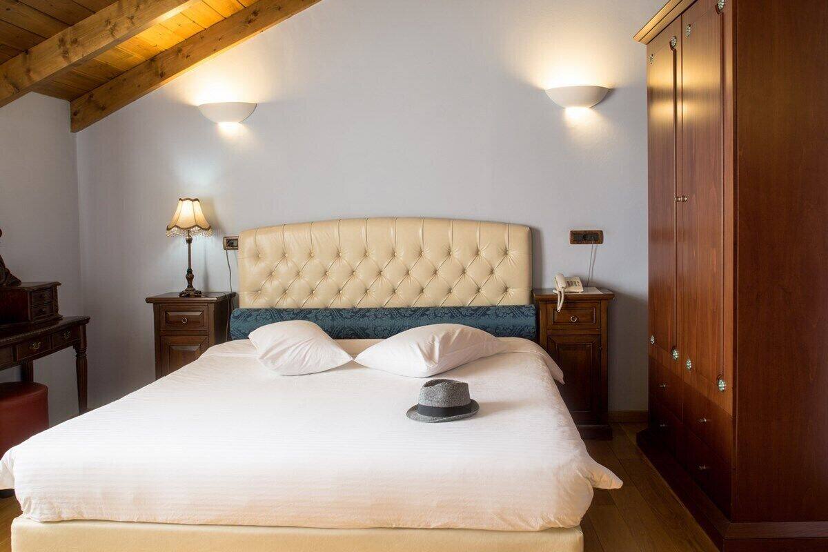A neatly made bed with a tufted headboard, a bedside lamp, and a telephone on a wooden nightstand.