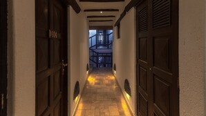 Un pasillo estrecho con puertas de madera y suelo de baldosas, que conduce a una escalera.