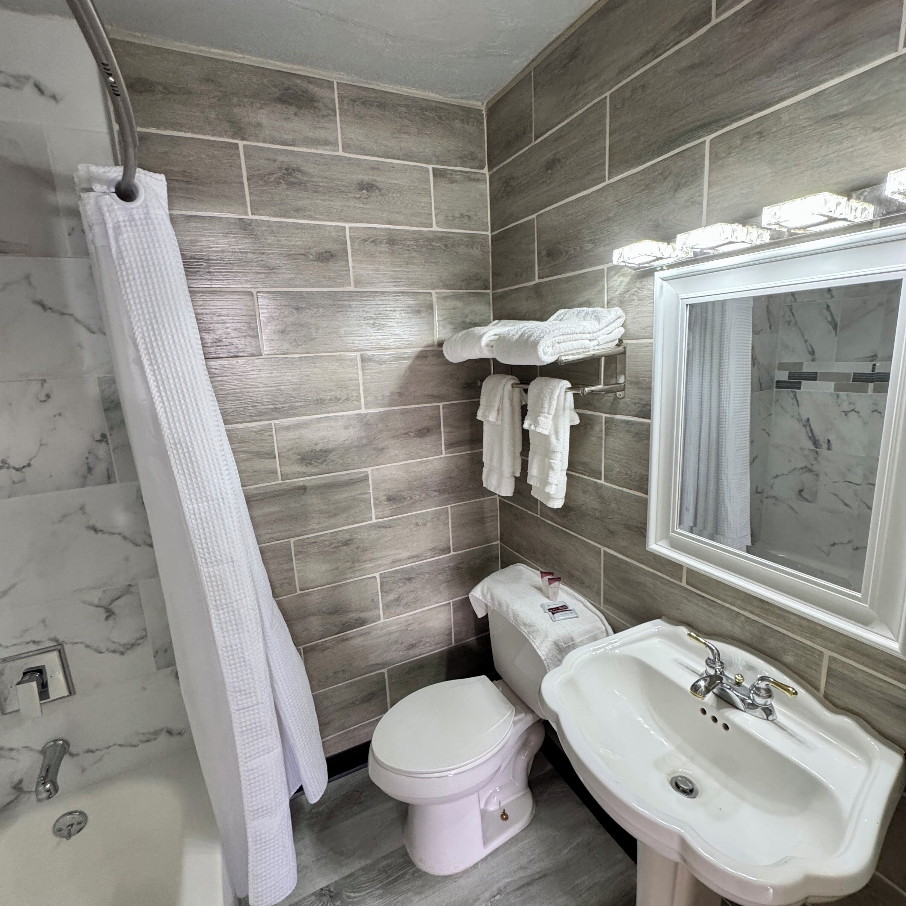 Et badeværelse med toilet, vask og spejl.