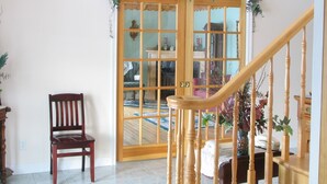 Eine Holztreppe mit Geländer, ein Holzstuhl und eine Glastür mit einem dekorativen Kranz.