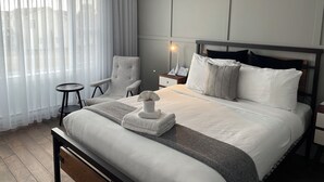 Une chambre d’hôtel avec un lit, une chaise, une table de chevet et une lampe.