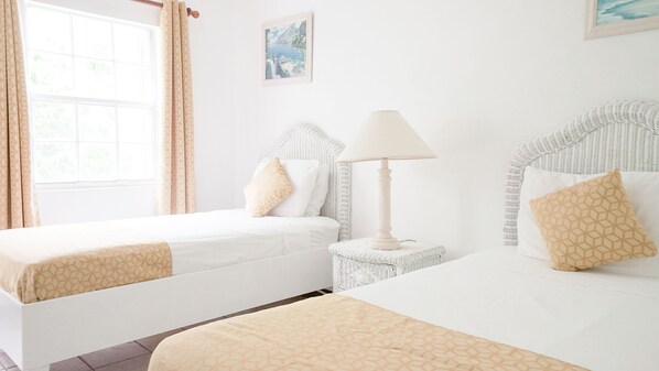 A hotel room with two beds, a bedside lamp, and a painting on the wall. - Royal Palms Hotel (South Hill)