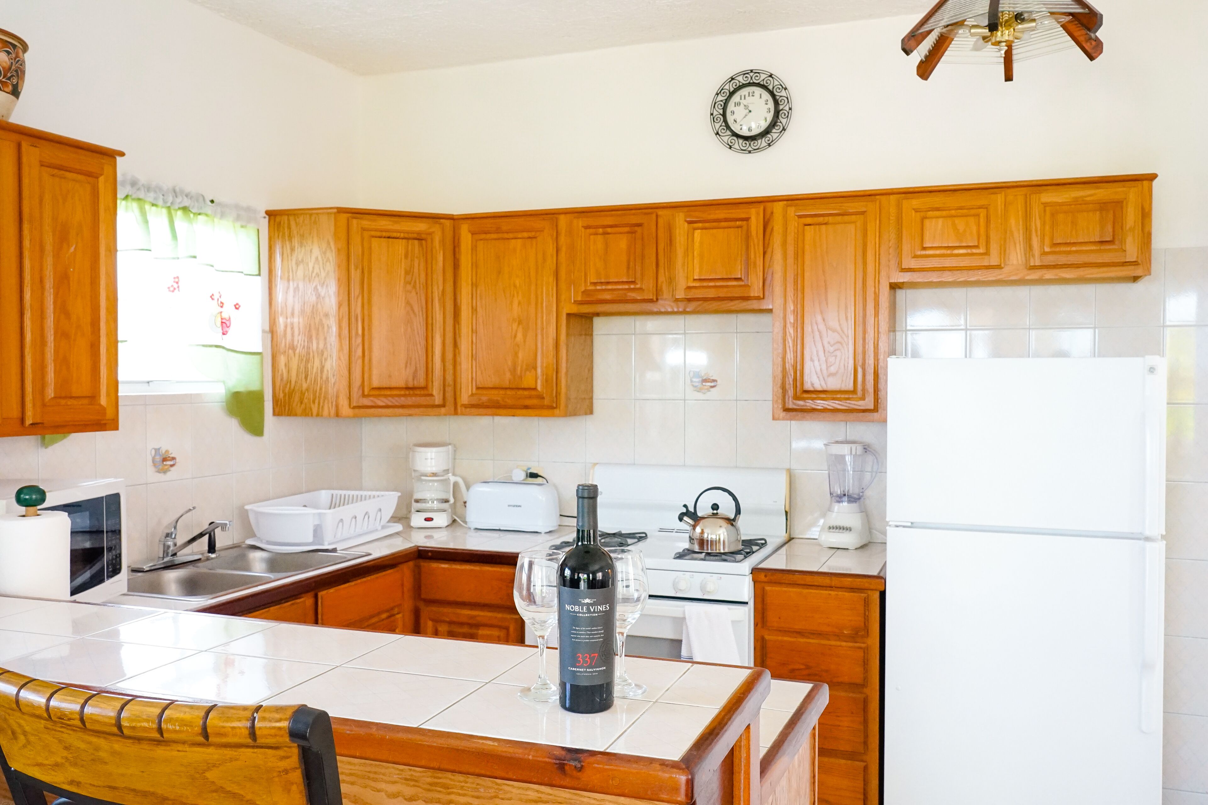 A kitchen with wooden cabinets, a white refrigerator, a stove, and a dining table with chairs.
