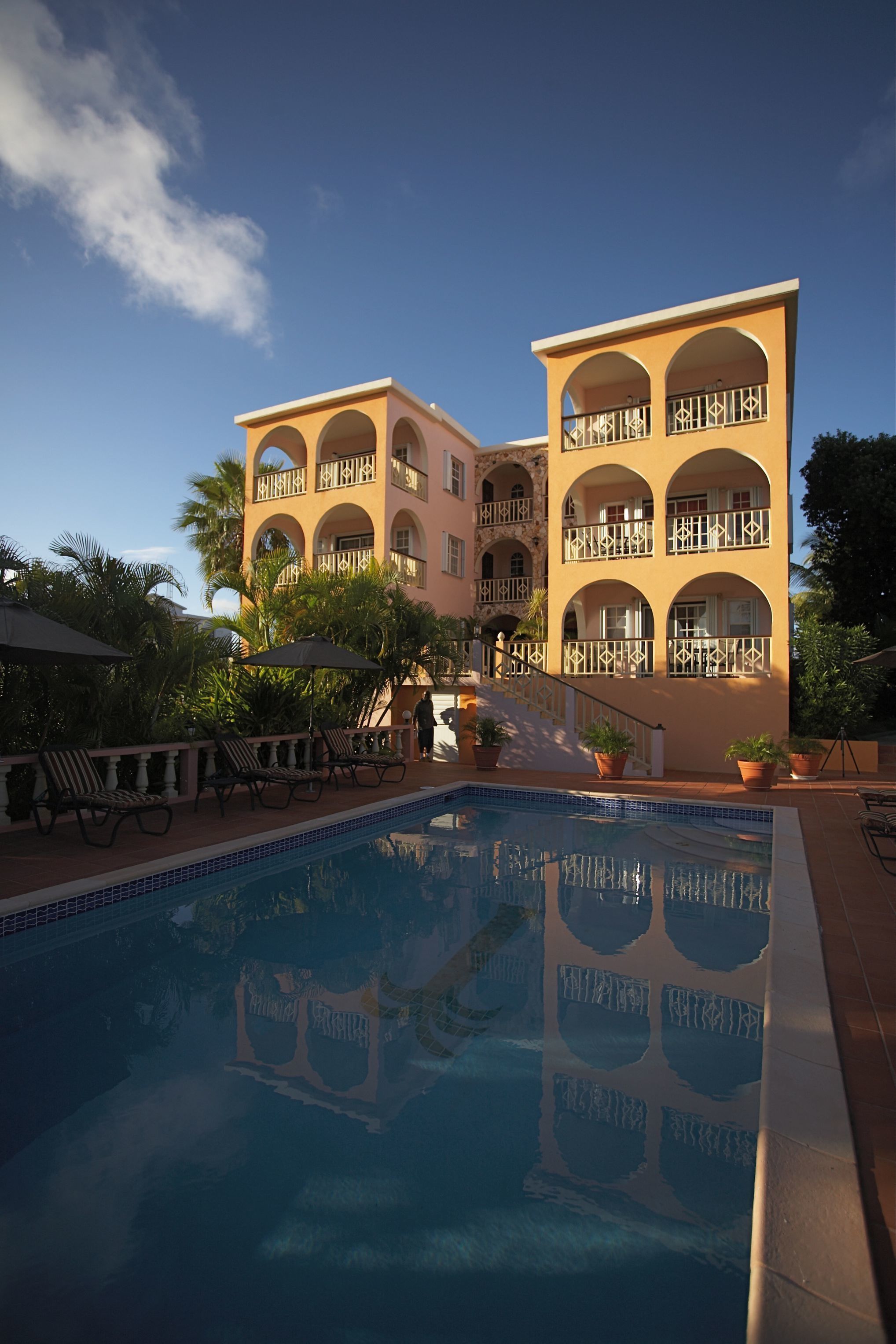 Un hotel con piscina, asientos exteriores y un edificio de varios pisos con balcones.