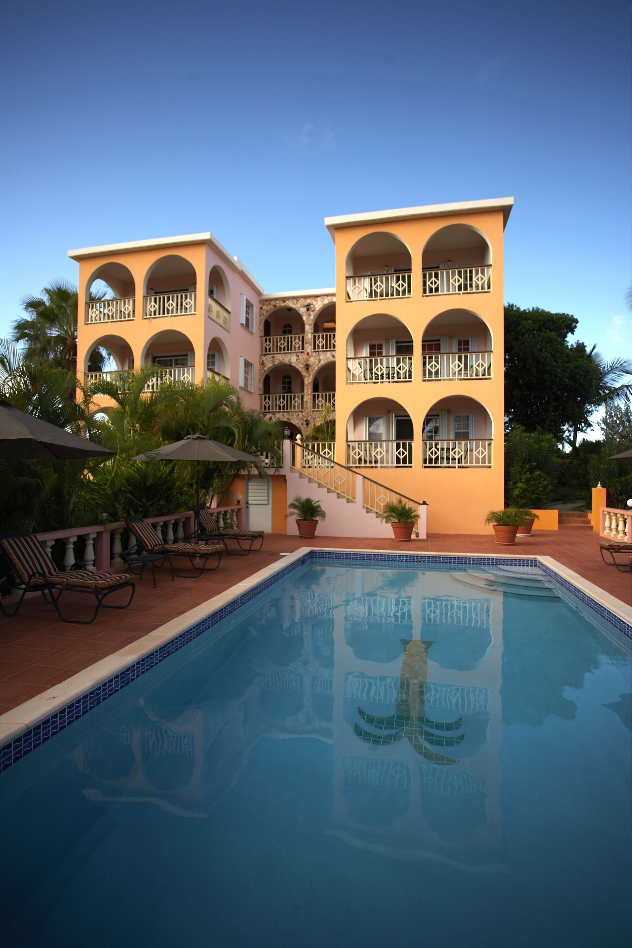 Un hotel con piscina, varios balcones y mobiliario para exteriores.