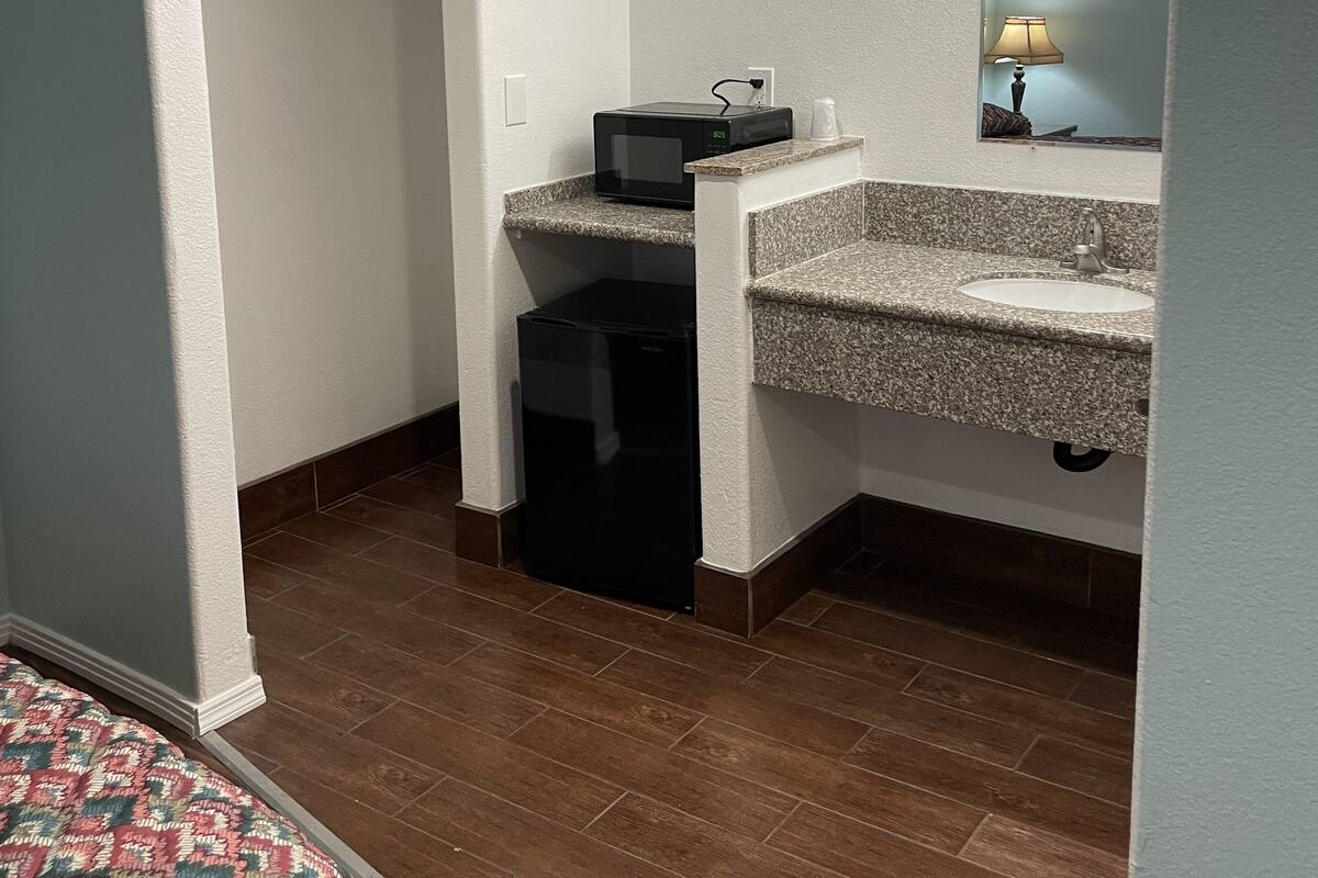 A small, compact bathroom with a sink, mirror, and a microwave.
