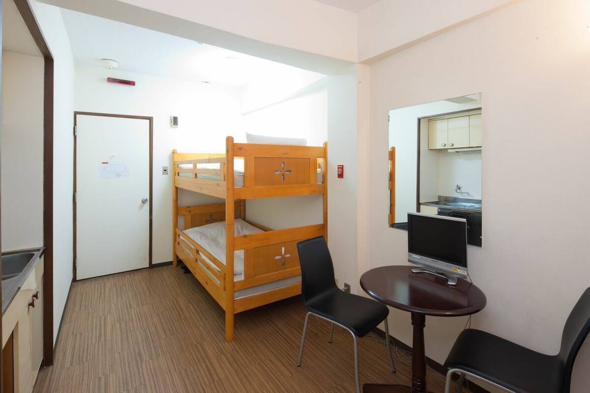 A bunk bed room with a desk, chair, and a television.