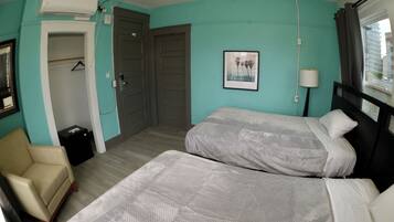 Une chambre avec deux lits, une chaise, une armoire et un tableau au mur.
