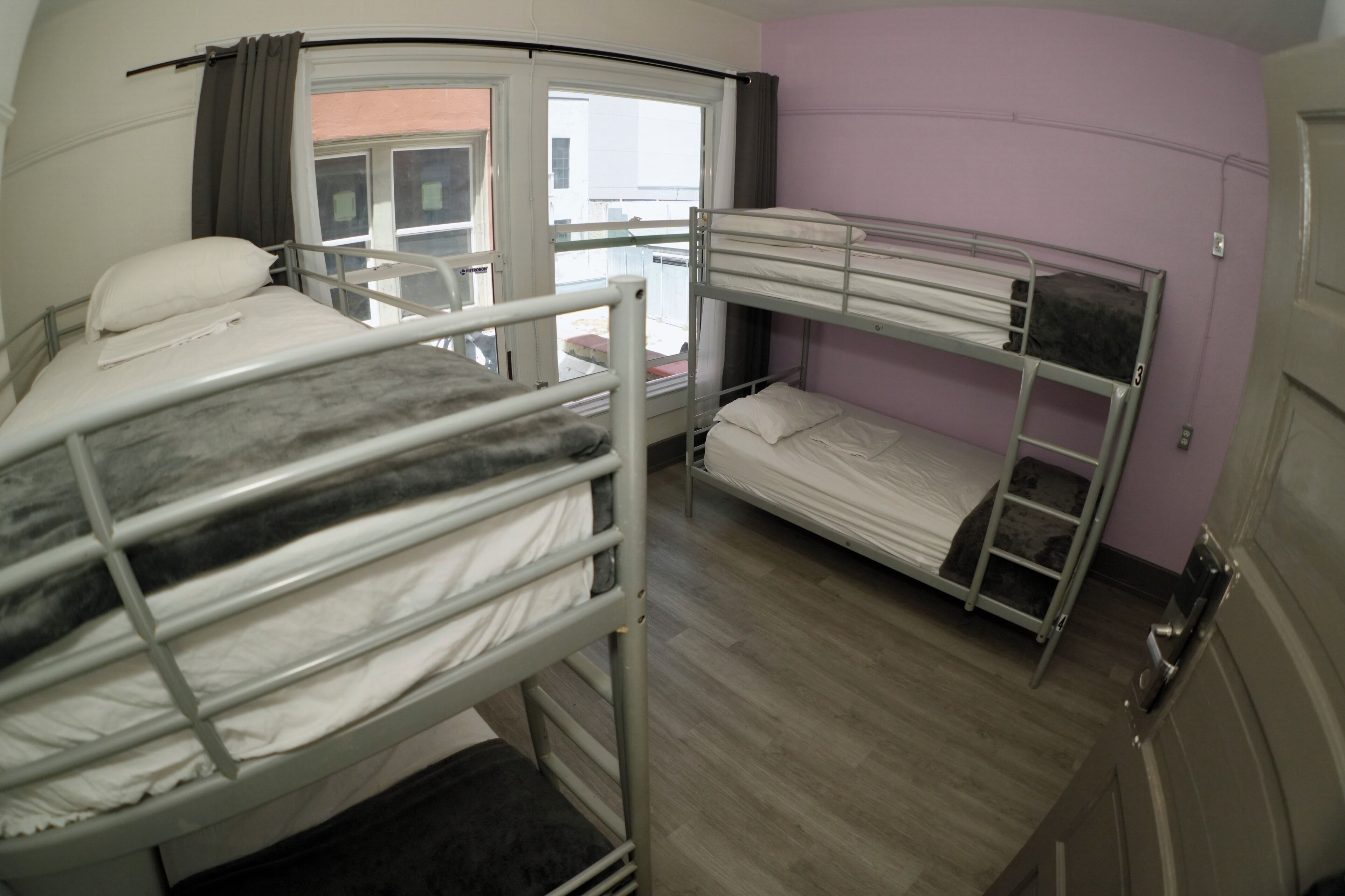 A bunk room with two bunk beds, a window with curtains, and a door.