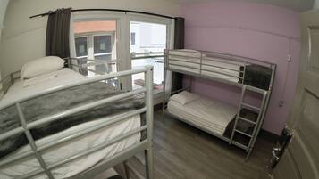 A bunk room with two bunk beds, a window with curtains, and a door.