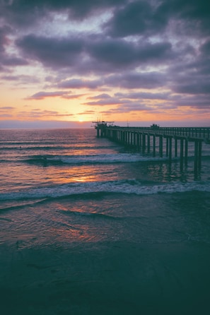 A pier extending into the ocean with waves crashing against it. - California Dreams Hostel - Downtown (San Diego)