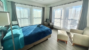 Ein modernes Hotelzimmer mit einem großen Bett, einem Schreibtisch, einem Sessel und einem Deckenventilator.