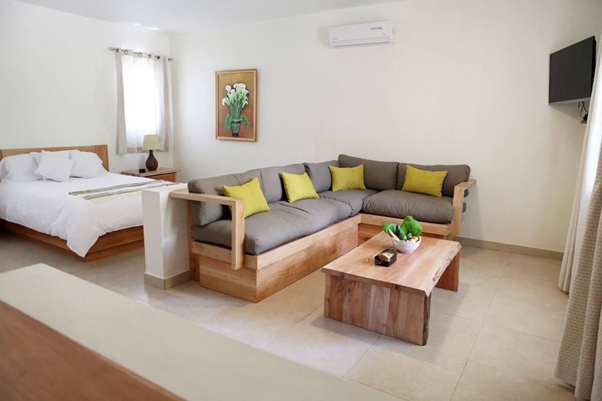 Ein modernes Zimmer mit einem Bett, einer Couch, einem Holztisch und einem Fernseher.