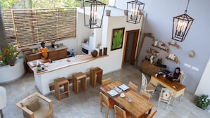 Une cuisine spacieuse avec des meubles en bois, un coin repas doté d’une grande table en bois et un bar.