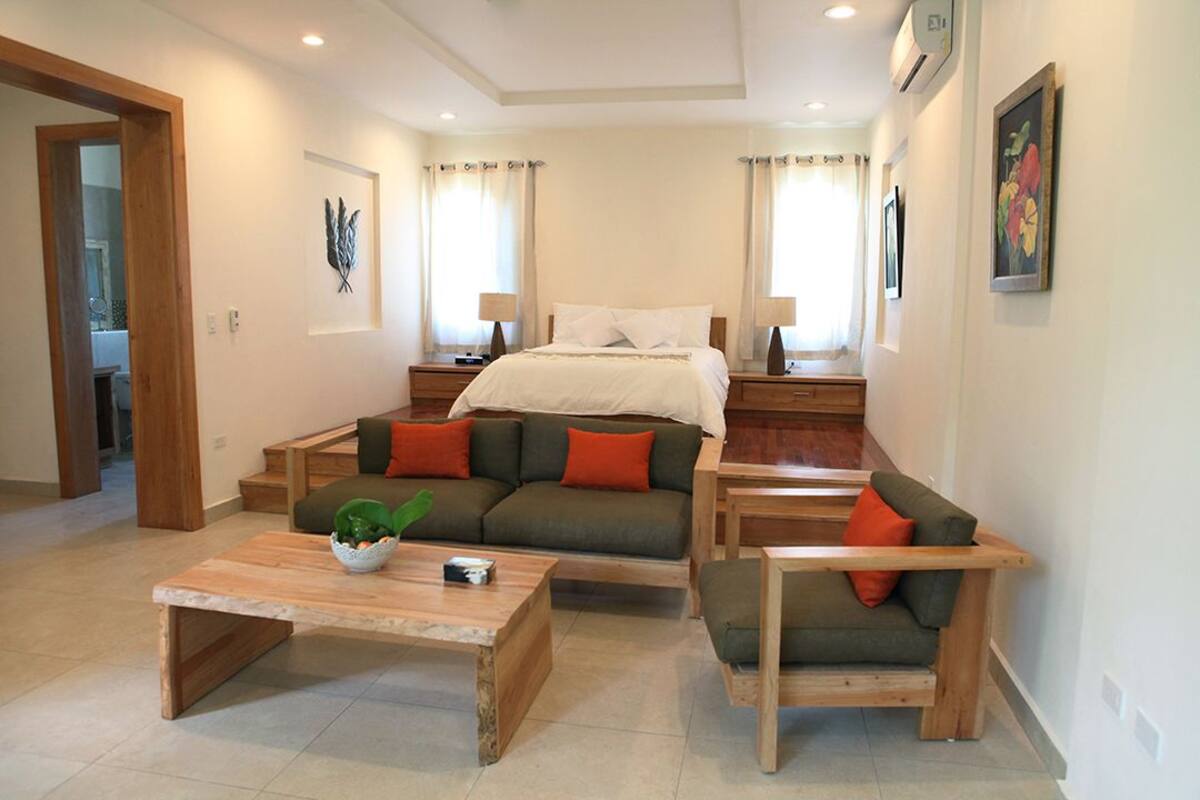 Ein modernes Wohnzimmer mit einer Couch, zwei Couchtischen und einem Bett.