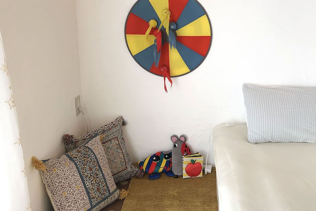 Un dormitorio con cama, almohadas, un reloj de pared y un juguete pequeño.