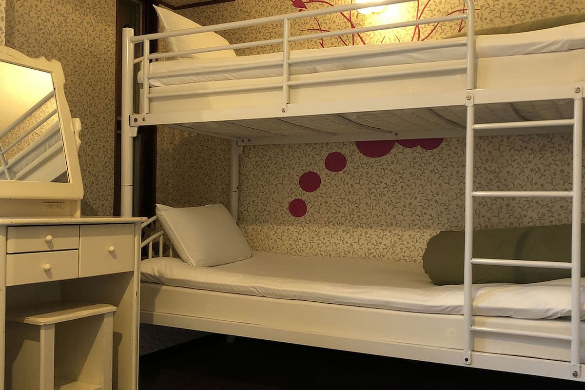 Habitación con literas, un escritorio y un espejo.