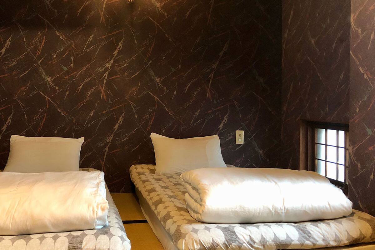 Una habitación con dos camas, cada una con ropa de cama blanca y cabeceros estampados.