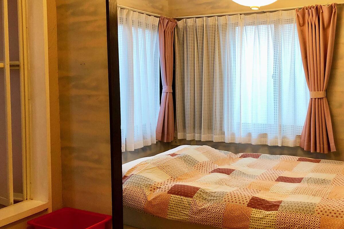Un dormitorio con cama, cortinas y ventana.