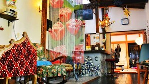 A cozy living room with a sofa, chairs, and a coffee table. There is a fireplace and a window with curtains. - Hostel Yume Nomad (Kobe)