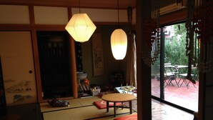 A traditional Japanese room with tatami flooring, a low table, and two hanging paper lanterns. - Hostel Yume Nomad (Kobe)