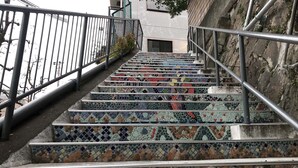A staircase with colorful mosaic steps and metal railings. - Hostel Yume Nomad (Kobe)