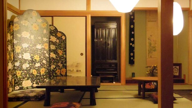 A traditional Japanese room with tatami flooring, a low table, and a sliding door. - Hostel Yume Nomad (Kobe)