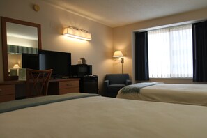 A hotel room with two beds, a desk with a television, a chair, a lamp, and a window with curtains. - Brentwood Inn & Suites (Rochester)