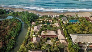 Luftaufnahme eines Küstenresorts mit Strand, Schwimmbad und Fluss.