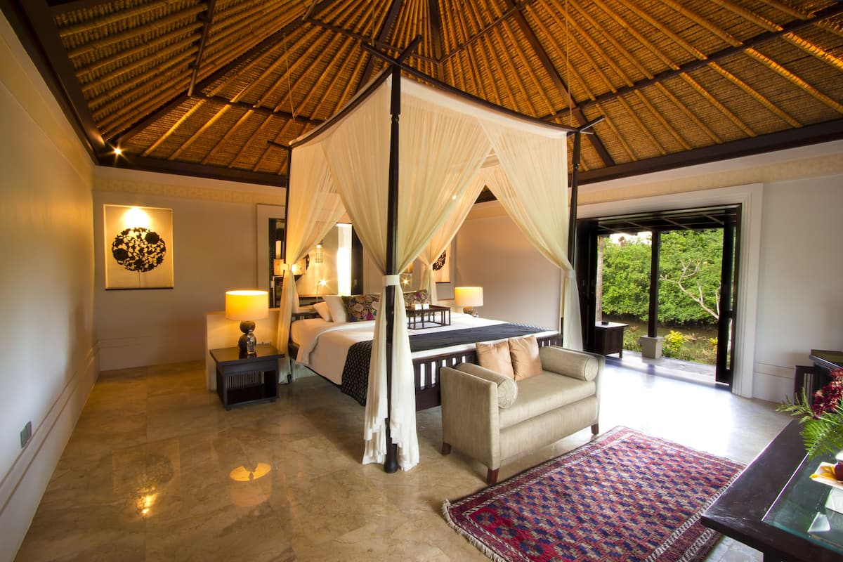 Un dormitorio con cama con dosel, un sofá y un ventanal grande.