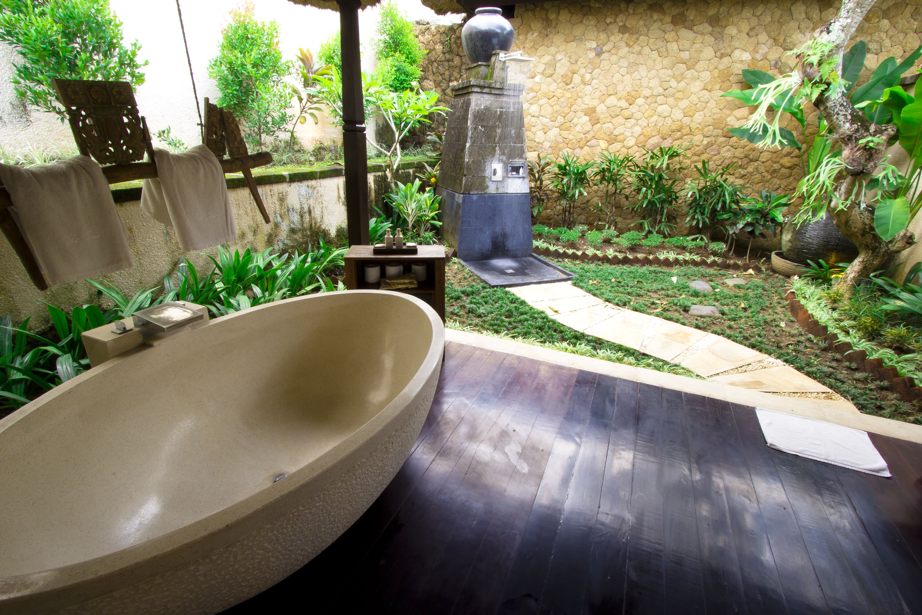 A spa area with a large stone basin, a wooden bench, and a stone wall.