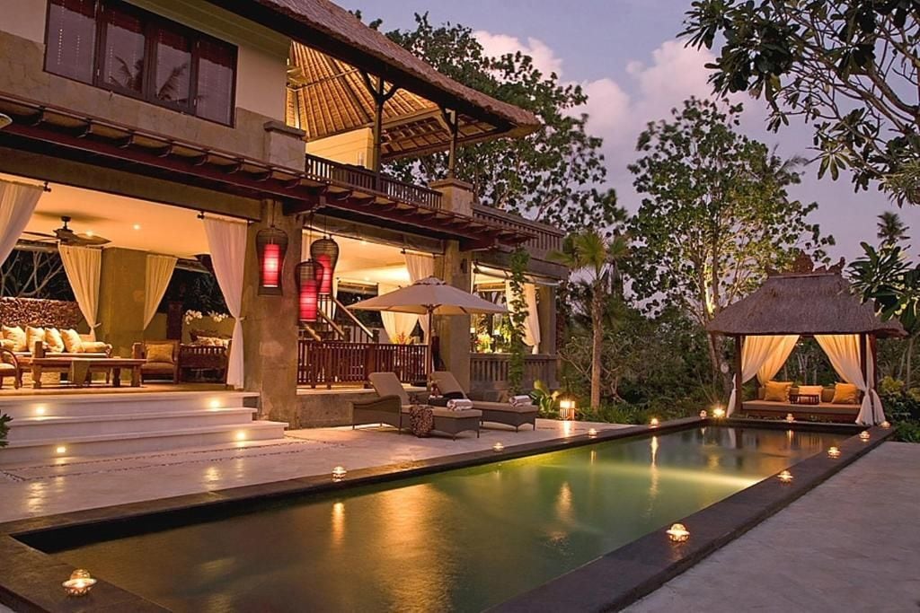 A poolside area with a lounge chair, a thatched-roof structure, and a staircase leading to an upper level.