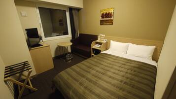A hotel room with a bed, a desk, a chair, a TV, and a window.