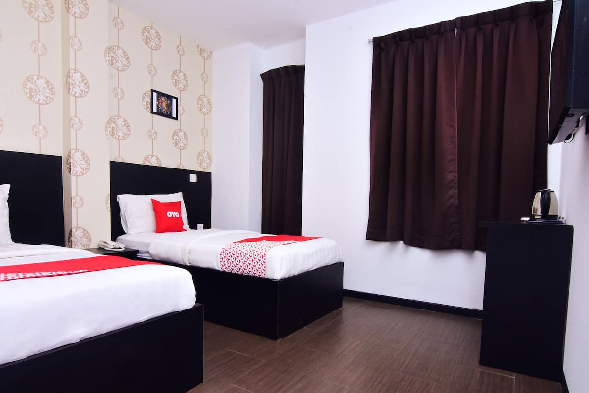 Habitación de hotel con dos camas, un escritorio pequeño, un teléfono y un cuadro en la pared.