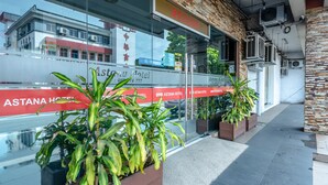 A hotel entrance with a 'Welcome' sign, glass doors, and potted plants.