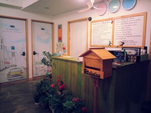 A reception area with a wooden desk, a clock, and a welcome sign. - Blue Backpackers Hostel (Busan)