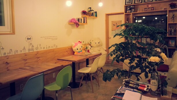 Un café acogedor con muebles de madera, una pared con un mural de la ciudad y una estantería con diversos objetos.
