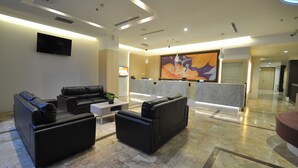 A modern lobby with black leather sofas, a flat-screen TV, and a large abstract painting. - DREAMTEL Jakarta (Jakarta)
