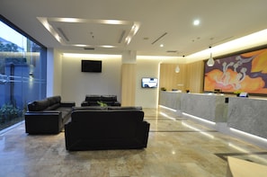 A modern lobby with a seating area, a reception desk, and a large window. - DREAMTEL Jakarta (Jakarta)