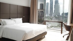 A modern bedroom with a large bed, a view of the cityscape, and a balcony with a chair. - DREAMTEL Jakarta (Jakarta)
