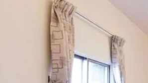 A hotel room with a bed, two pillows, a window with curtains, and a headboard.