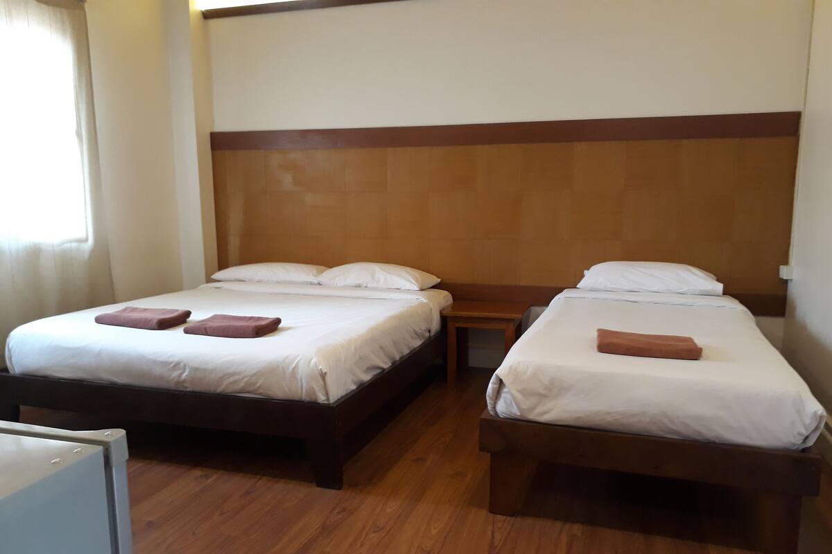 A hotel room with two single beds, wooden headboards, and a wooden floor.