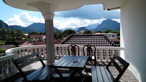 A terrace with a table and chairs, overlooking a mountainous landscape. - Laos Haven Hotel (Vang Vieng)