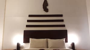 A neatly made bed with a headboard featuring horizontal wooden panels and a decorative element above it. - Laos Haven Hotel (Vang Vieng)